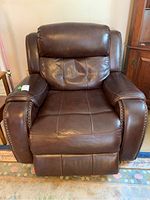 Front view of brown leather electric recliner lift chair with footrest extended and nailhead trim