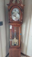 Full view of Ridgeway grandmother clock in wooden casing showing clock face, pendulum, and weights.