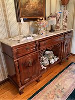 Wooden buffet server with polished white marble top, three drawers, two cabinets and open mirrored shelf. Rich dark wood finish with intricate details and pulls.
