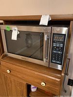 Front-left angle view of Magic Chef microwave oven showing door, handle, and control panel with digital display and keypad.