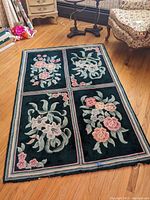 Full view of floral panel area rug laid out on wooden floor, showing four distinct flower designs in rectangular panels with a bordered edge.