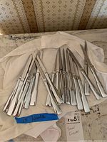 18 Towle stainless steel dinner knives arranged on a white cloth, showing polished handles and blades.