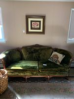 Full front view of vintage green velvet settee showing loose cushions and ornate wooden frame.