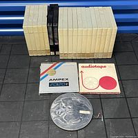 Lot of BASF large reel digital master tapes with two additional boxes labeled Ampex and Audiotape, and a large metal reel.