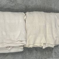 Photo of two folded cream cotton blankets showing texture and weave pattern.