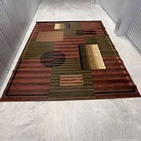 Top-down view of geometric area rug on concrete floor, showing full pattern and shape.
