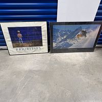 Two inspirational posters titled 'Priorities' and 'Challenges' side by side on floor, showing frames with some damage.
