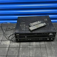 Yamaha HTR-5550 AV Receiver with two remotes on top, showing front and top vented panel.