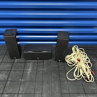 Full set showing two vertical satellite Yamaha speakers, one horizontal center Yamaha speaker, and white speaker cables coiled on the floor.