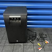 Black Yamaha subwoofer with cables visible on the floor, front view