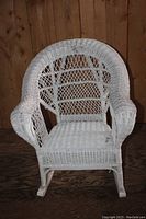 Front view of antique white wicker kids rocking chair showing detailed woven pattern and armrests.