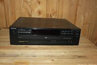 Front view of Sony 5-disc CD player showing control panel, display, and tray.