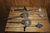 Two solar garden lights with glass globe covers and metal stakes, plus three metal flower garden stakes with white petals on wooden surface.