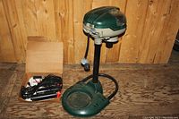 View of green propane mosquito magnet device with separate box of electrical cords and control box.