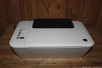 Top front angled view of the white HP printer showing control panel and paper output tray