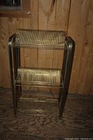 Front view of the vintage metal record holder showing the top and middle tiers with vertical slots for records.