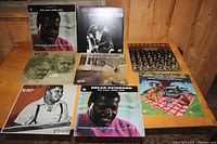 Photo showing 8 vinyl records, prominently two different Oscar Peterson albums with photographic covers and several other jazz-themed records with illustrated and photographic covers.