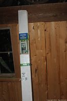 Boxed retractable screen door leaning against wooden wall.