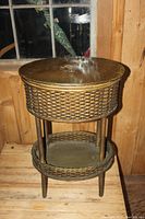 Full view of the vintage wicker sewing basket showing oval shape, four legs and lower round wicker shelf.