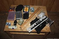 Lot overview including table legs, vintage electronics, pencil cases, and boxed games on a wooden table surface