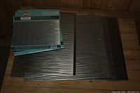 Photo showing multiple stacked plastic backsplash sheets with textured linear pattern on wooden floor.