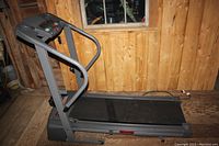 Side view of treadmill in unfolded position showing walking belt and handrails