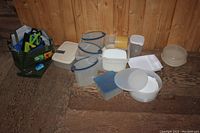 Displays the full collection of assorted Tupperware containers including various shapes and sizes on wooden floor