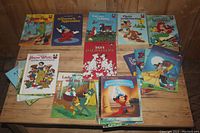 Photo showing multiple Disney children's books laid out on wooden surface including Lady and the Tramp, 101 Dalmatians, Snow White and the Seven Dwarfs, and others.