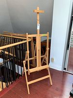 Full view of Mabef adjustable wooden art easel next to staircase showing general form and size.