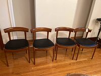 Four wooden chairs with black vinyl seats arranged side by side