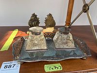 Front view of ink bottles on silver plate tray with brass ship bookends in background.