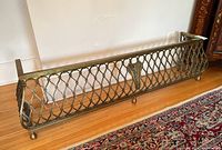 Front view of brass fireplace gate showing lattice design and Caduceus emblem