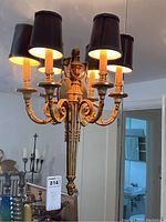Frontal view of one sconce mounted in front of a mirror showing three lights and black fabric shades