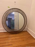Front view of the round mirror showing the circular reflective surface and the steel rod frame.