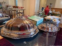 Front view of large covered turkey server and smaller vegetable server side by side on glass table