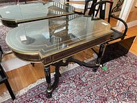 Front three-quarter view showing overall table shape, glass top, drawer front and stretcher base