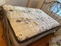 Angled view of mattress on frame showing quilted top surface and pattern