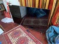 Front view of TV on floor with stands and remote on rug