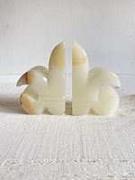 Front view showing the symmetrical fleur-de-lis shape on the carved stone bookends with the natural color veining visible.