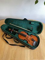 Learner violin and bow inside green-lined protective case, showing overall condition and layout