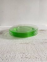 Stack of four translucent green-tinted glass plates viewed from the side showing faint green color.