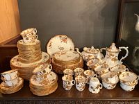 Full view of dinnerware set with stacked plates on left, cups and saucers front, pots on right