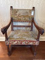 Full front view of armchair showing carved arms, turned legs, and tapestry upholstery