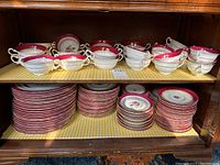 Top shelf showing cream soup bowls and teacups with red border floral pattern