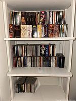 Three-shelf white cabinet filled with classical CD box sets and individual discs
