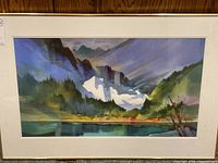 Framed watercolor landscape by Robert Meechan leaning against wood panel wall, full view