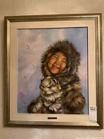Framed oil painting of smiling Inuit child with husky dog, gold-tone frame and beige mat