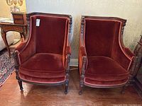 Front view showing both burgundy velvet upholstered armchairs with carved wood frames