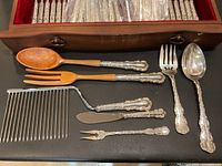Loose serving pieces laid out: carving knife, carving fork, small two-prong fork, large ladle, large fork, wooden-handled salad servers