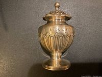 Front view of pounce pot on black background showing body and base